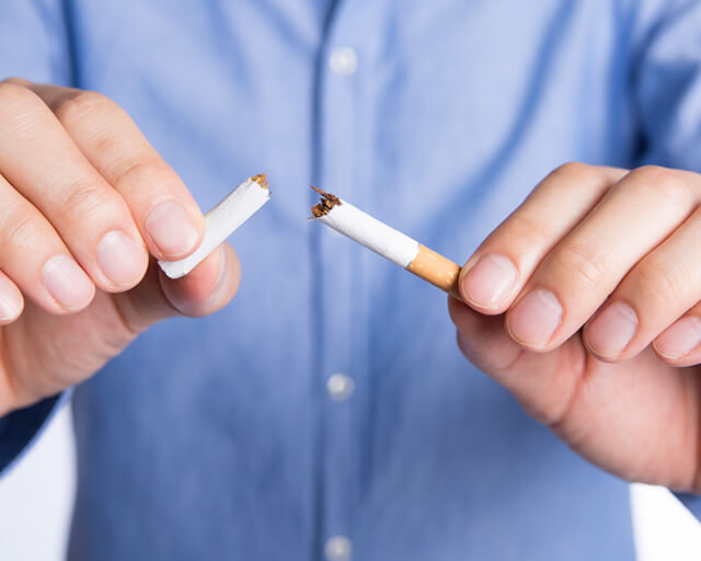 禁煙外来でのサポートを象徴する、タバコを手で折って禁煙を決意する人の写真。豊中駅前さかい内科・循環器クリニックの禁煙治療イメージ。