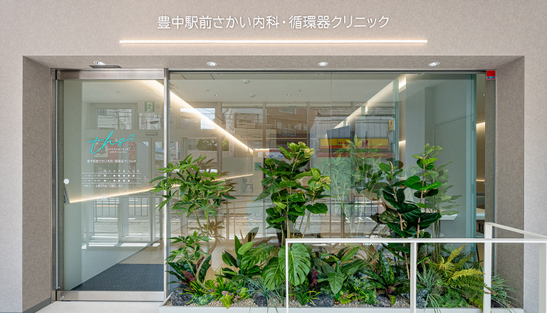 豊中駅前さかい内科・循環器クリニックのエントランス。ミントブルーを基調とした清潔感ある外観と、駅近で通いやすい立地が特徴です。